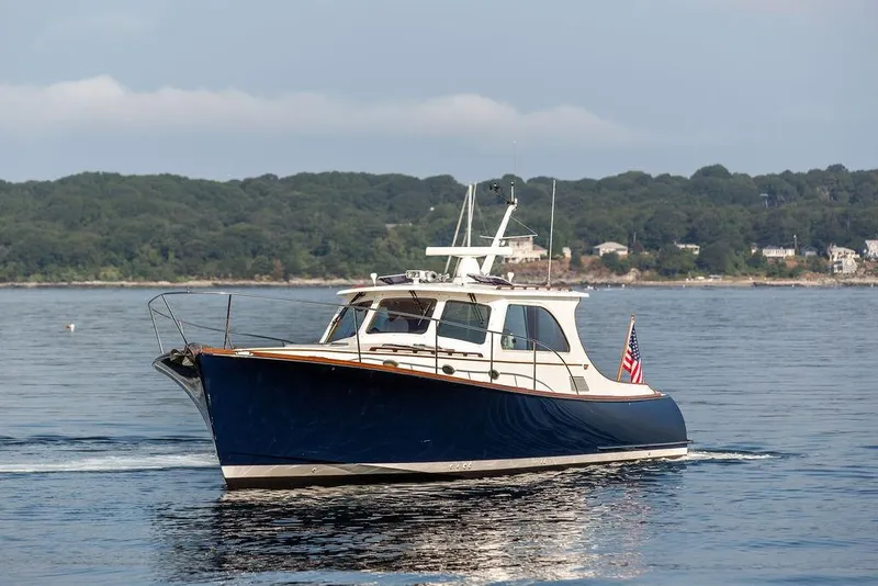 Slide: The Image of 2002 Hinckley Talaria 44 yacht cruising on calm waters with scenic shoreline backdrop. - 4