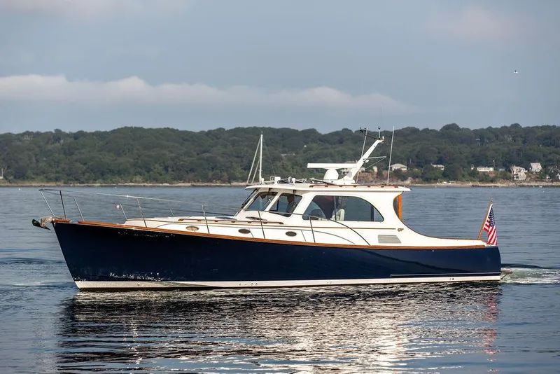 Slide: The Image of 2002 Hinckley Talaria 44 yacht cruising on calm waters with scenic shoreline backdrop. - 5
