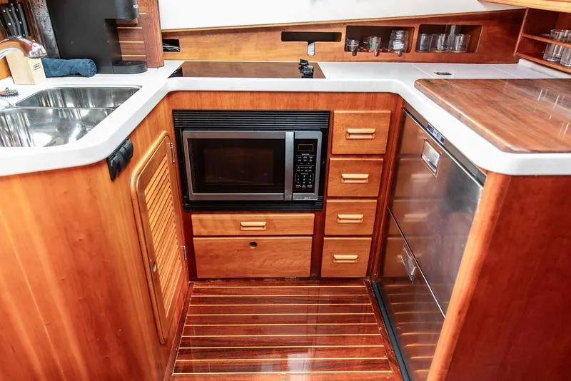 Slide: The Image of 2002 Hinckley Talaria 44 yacht kitchen with wood cabinetry, microwave, and stainless steel sink. - 29