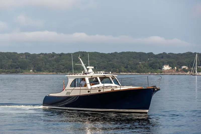 Slide: The Image of 2002 Hinckley Talaria 44 yacht cruising on calm waters near a forested shoreline. - 3