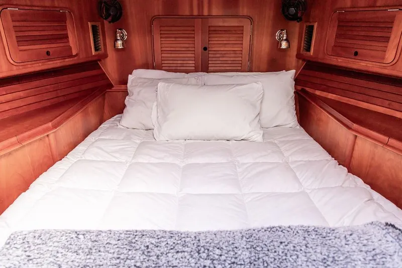 Slide: The Image of Cozy cabin interior of 2002 Hinckley Talaria 44 with plush bedding and wooden accents. - 32