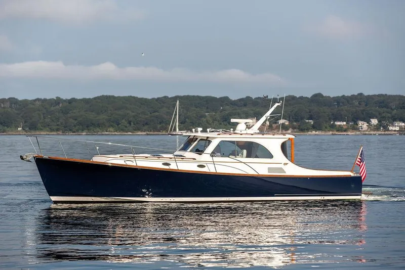 Slide: The Image of 2002 Hinckley Talaria 44 yacht cruising on calm waters with scenic shoreline backdrop. - 6