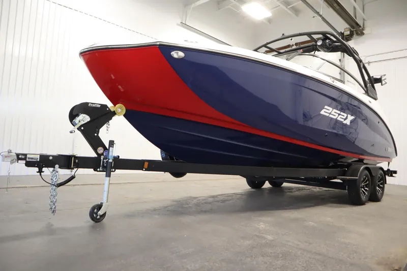 Slide: The Image of 2025 Yamaha Boats 252XE on trailer, featuring sleek red and blue design in a showroom. - 46