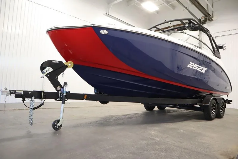 Slide: The Image of 2025 Yamaha Boats 252XE on trailer, featuring sleek red and blue design in a showroom. - 50
