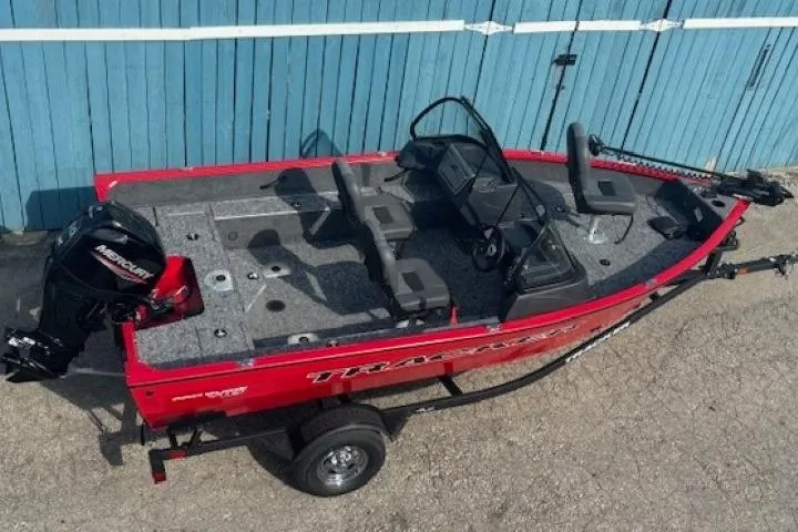 Slide: The Image of 2026 Tracker Pro Guide V-16 WT boat, red exterior, parked on a trailer near a blue wall. - 5