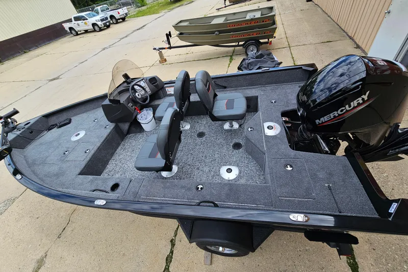 The Image of 2026 Tracker Pro Guide V-16 SC fishing boat with Mercury engine, parked outdoors. - 0