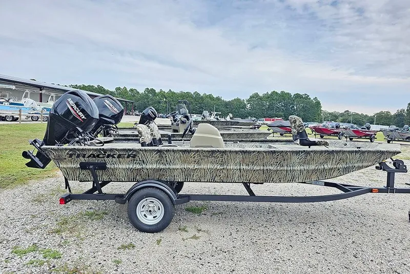 The Image of 2026 Tracker Grizzly 1754 SC boat on trailer, camo design, parked outdoors. - 1