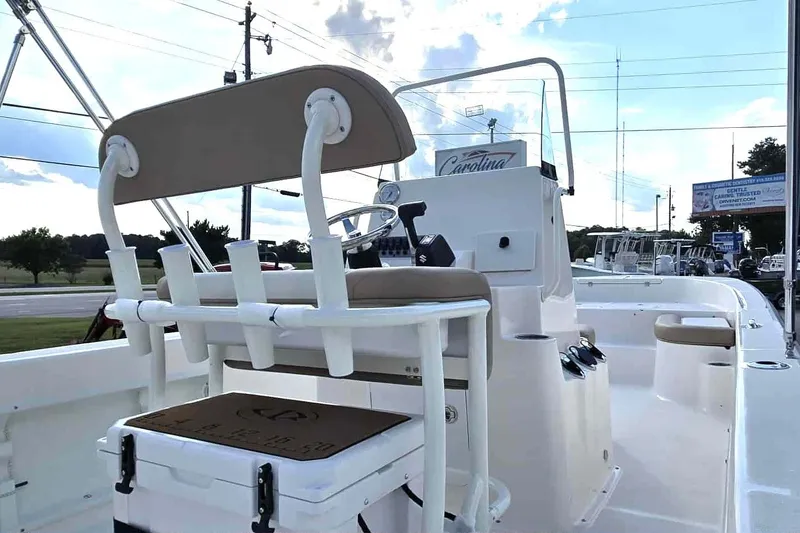 Slide: The Image of 2026 Sundance DX22 boat interior with seating and steering console, parked outdoors. - 10