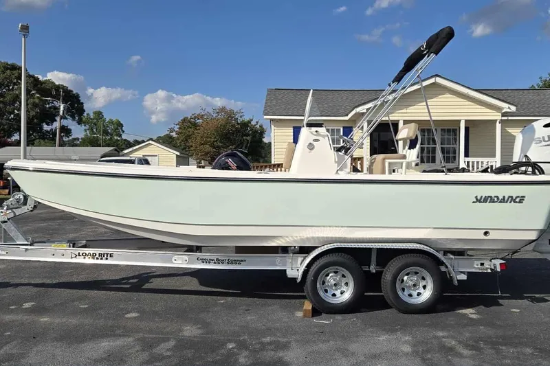 Slide: The Image of 2026 Sundance DX22 boat on trailer, parked outdoors under clear sky. - 3