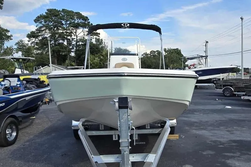 Slide: The Image of 2026 Sundance DX22 boat on trailer, parked outdoors with other boats nearby. - 8