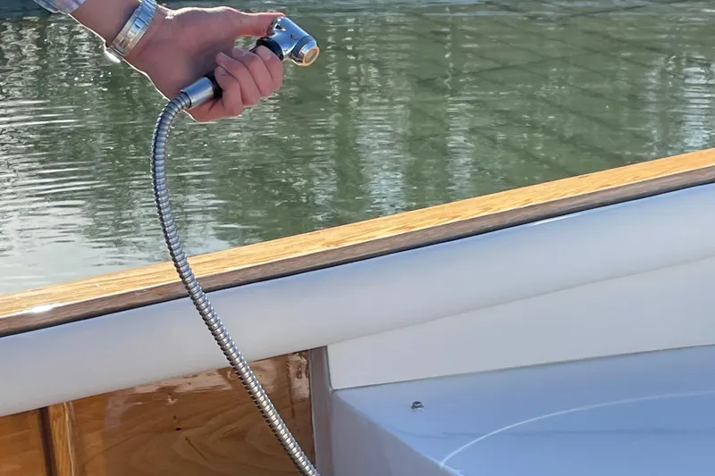 Slide: The Image of Hand holding a shower hose on Dorrien Yachts 160T 1/1, 2025 model, near water. - 25