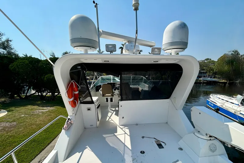 Slide: The Image of 2000 Pacific Mariner 65 Motoryacht with radar equipment, docked near lush greenery. - 66