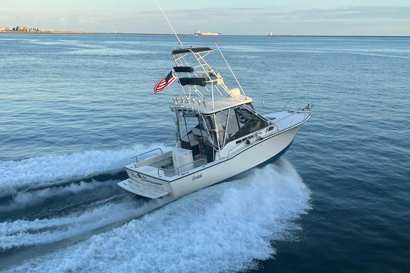 The Image of 2004 Carolina Classic Express Cabin Cruiser navigating ocean waters with American flag. - 0