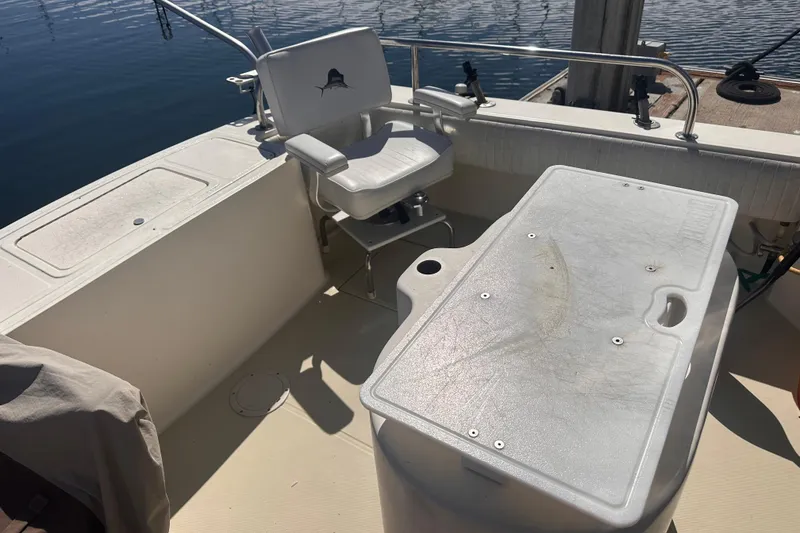 Slide: The Image of 2004 Carolina Classic Express Cabin Cruiser deck with chair and storage compartment. - 10