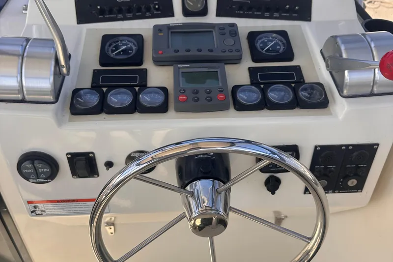 Slide: The Image of Dashboard of 2004 Carolina Classic Express Cabin Cruiser with steering wheel and gauges. - 12