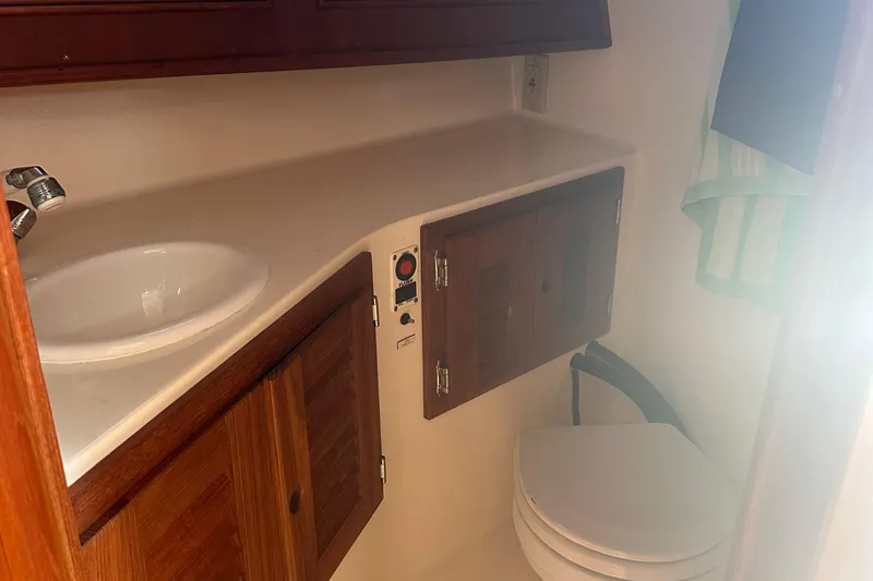 Slide: The Image of 2004 Carolina Classic Express Cabin Cruiser bathroom with sink, wooden cabinets, and toilet. - 21