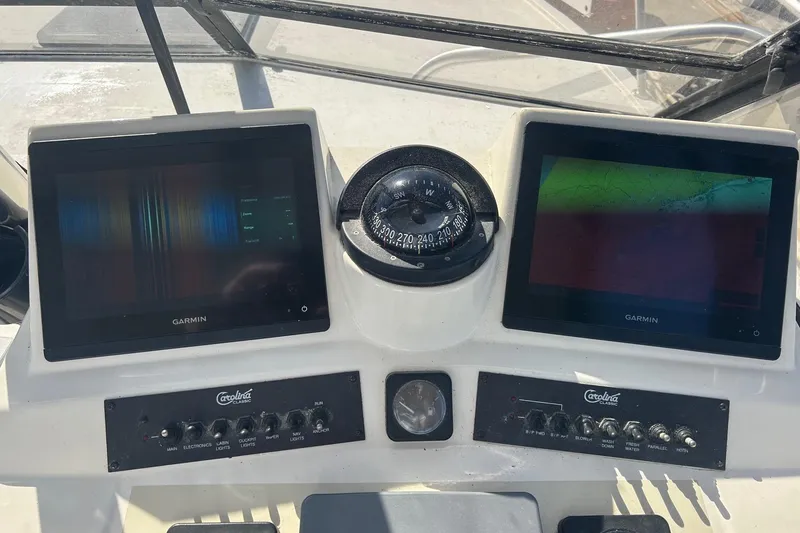 Slide: The Image of Control panel of a 2004 Carolina Classic sport fishing boat with Garmin displays and compass. - 8