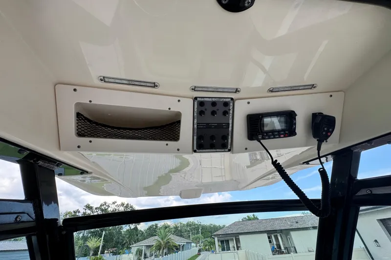Slide: The Image of 2020 Scout 251 XSS boat interior with steering console and seating, parked on brick driveway. - 17