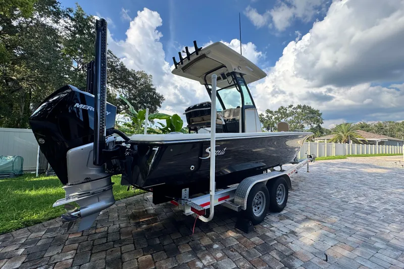 Slide: The Image of 2020 Scout 251 XSS boat on water near modern waterfront buildings. - 2