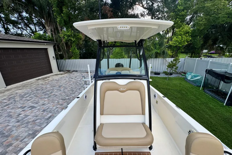 Slide: The Image of 2020 Scout 251 XSS boat with seating, parked in a driveway near greenery. - 35