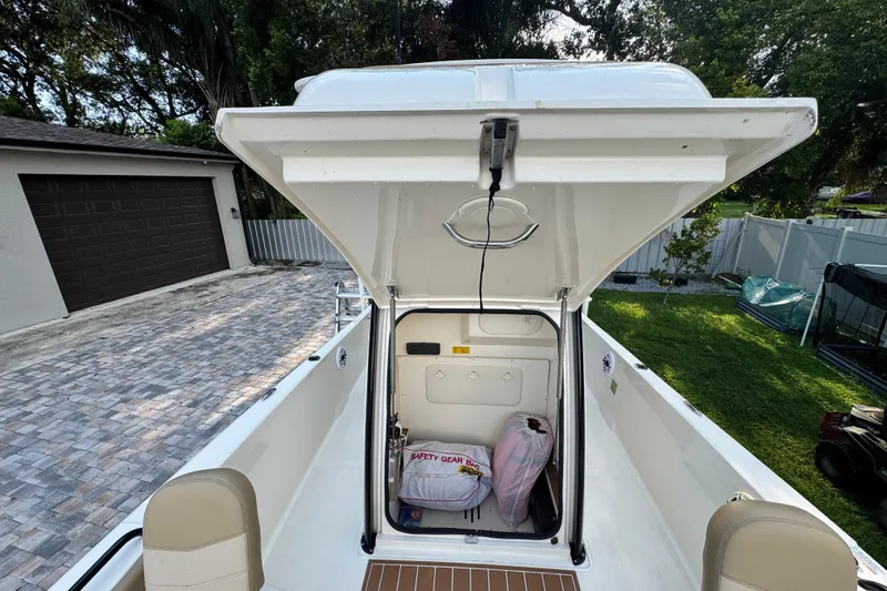 Slide: The Image of 2020 Scout 251 XSS boat with open storage compartment in a residential driveway. - 36