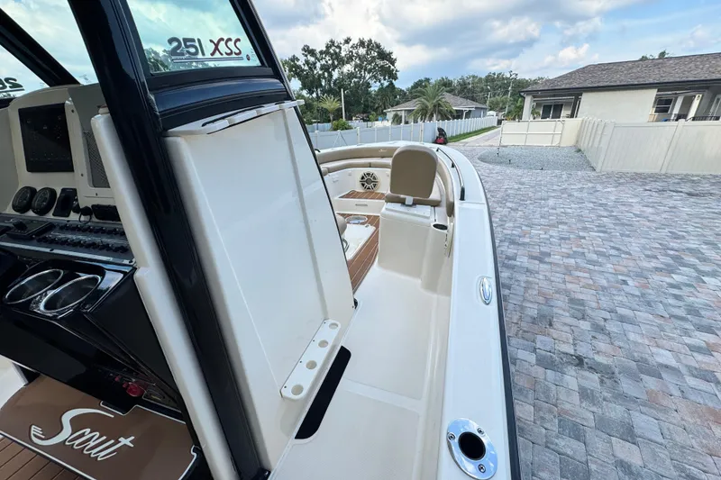 Slide: The Image of 2020 Scout 251 XSS boat interior with dashboard and seating, parked on a paved driveway. - 38