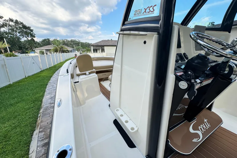 Slide: The Image of 2020 Scout 251 XSS boat interior with steering wheel and seating, parked near a white fence. - 39