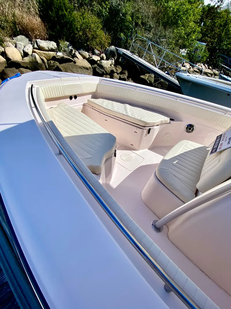 Slide: The Image of 2014 Grady-White Canyon 306 boat with cushioned seating, docked near rocky shoreline. - 1