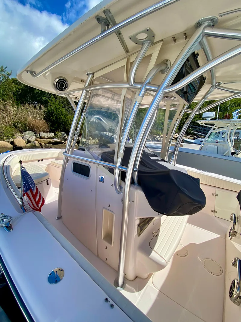 Slide: The Image of 2014 Grady-White Canyon 306 boat with T-top and American flag, docked under blue sky. - 5