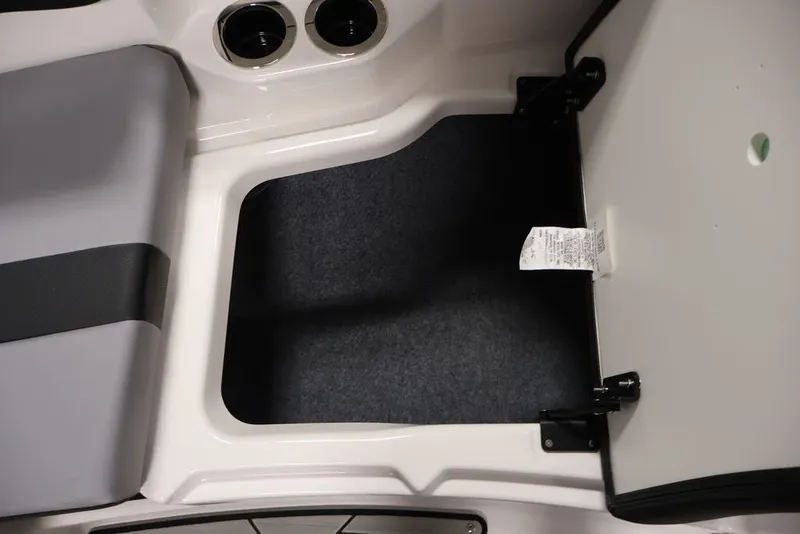 Slide: The Image of Interior storage compartment of 2026 Yamaha Boats 222XE, featuring cup holders and cushioned seating. - 17