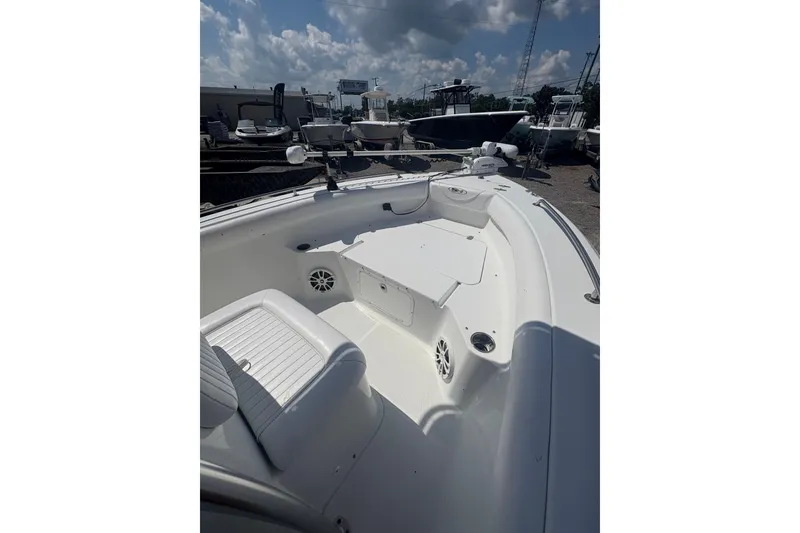 Slide: The Image of 2010 Sea Hunt Triton 202 boat interior with seating and storage, under a partly cloudy sky. - 10