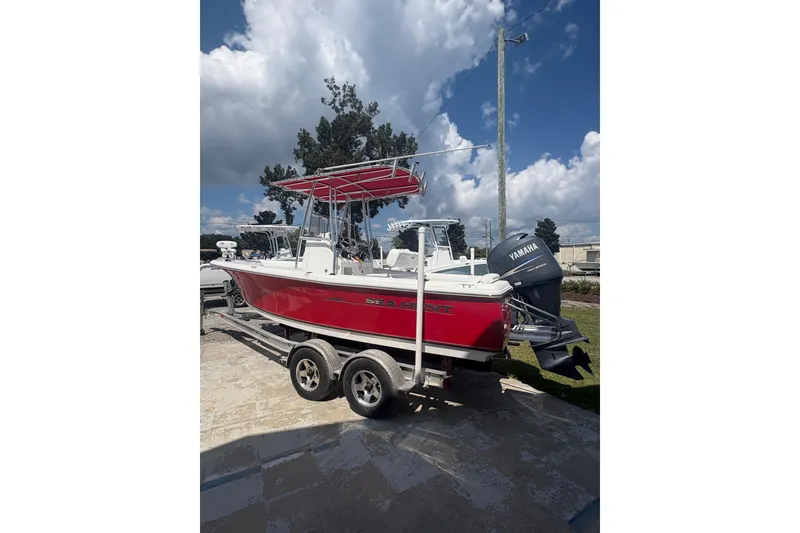 Slide: The Image of 2010 Sea Hunt Triton 202 boat with red hull on a trailer, under a blue sky. - 4