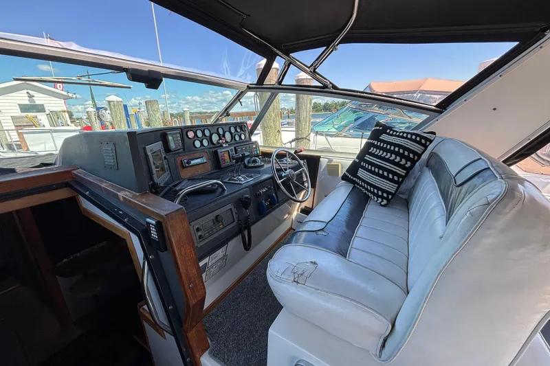 Slide: The Image of 1989 Sea Ray 400 Express Cruiser helm with vintage controls and cushioned seating. - 11