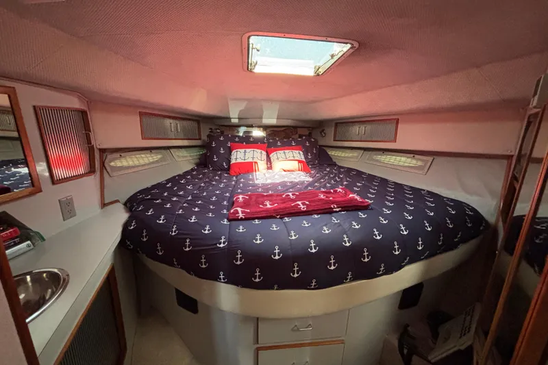Slide: The Image of Cozy cabin interior of 1989 Sea Ray 400 Express Cruiser with nautical-themed bedding. - 19