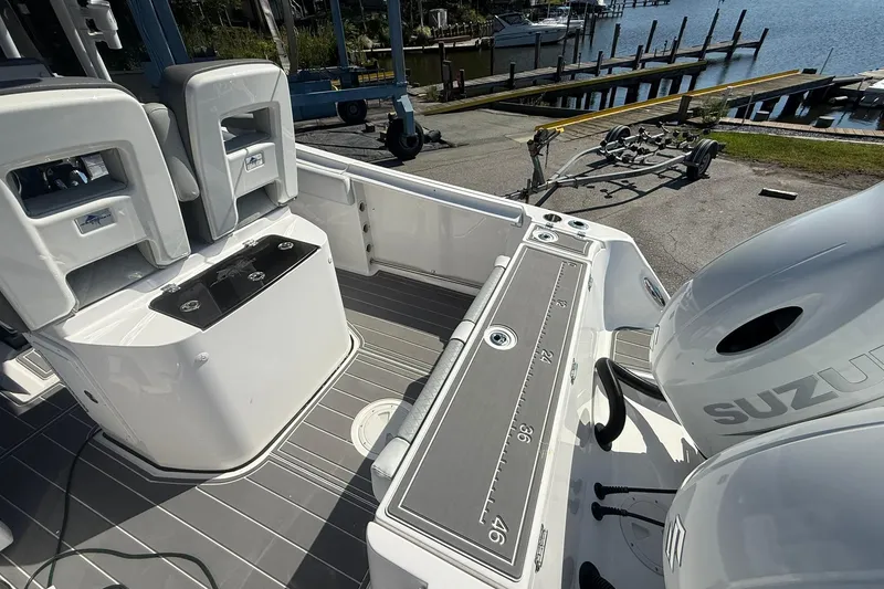 Slide: The Image of 2023 Aquasport 2500 Center Console boat interior with Suzuki engine, dockside view. - 10
