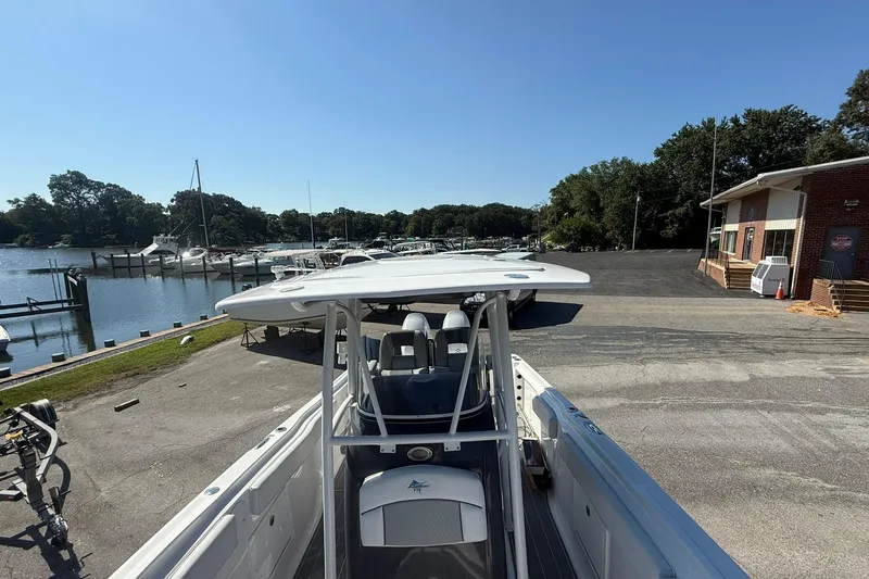 Slide: The Image of 2023 Aquasport 2500 Center Console boat docked near a marina under clear blue skies. - 15