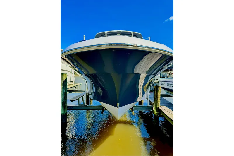 Slide: The Image of 2023 Aquasport 2500 Center Console boat docked, reflecting on water under clear blue sky. - 7