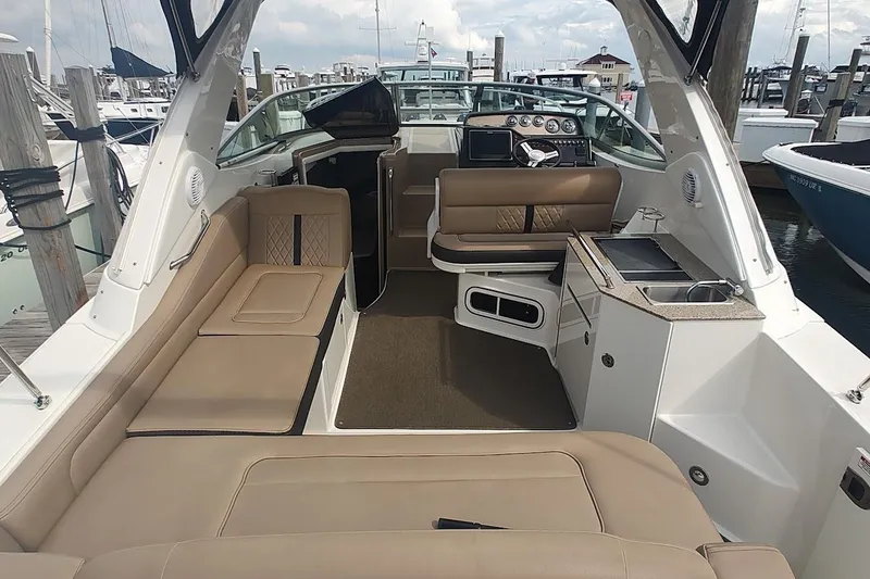 Slide: The Image of 2017 Sea Ray Sundancer 310 interior with beige seating and helm at marina. - 14