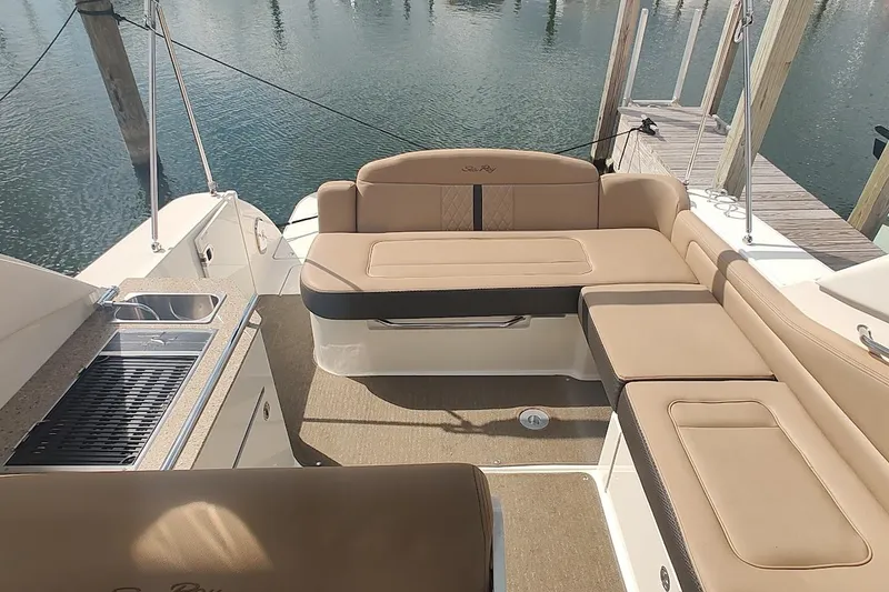 Slide: The Image of 2017 Sea Ray Sundancer 310 boat interior with beige seating and kitchenette by the water. - 15