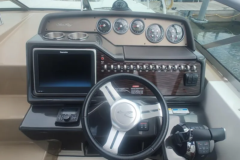 Slide: The Image of 2017 Sea Ray Sundancer 310 helm with steering wheel, gauges, and navigation display. - 22