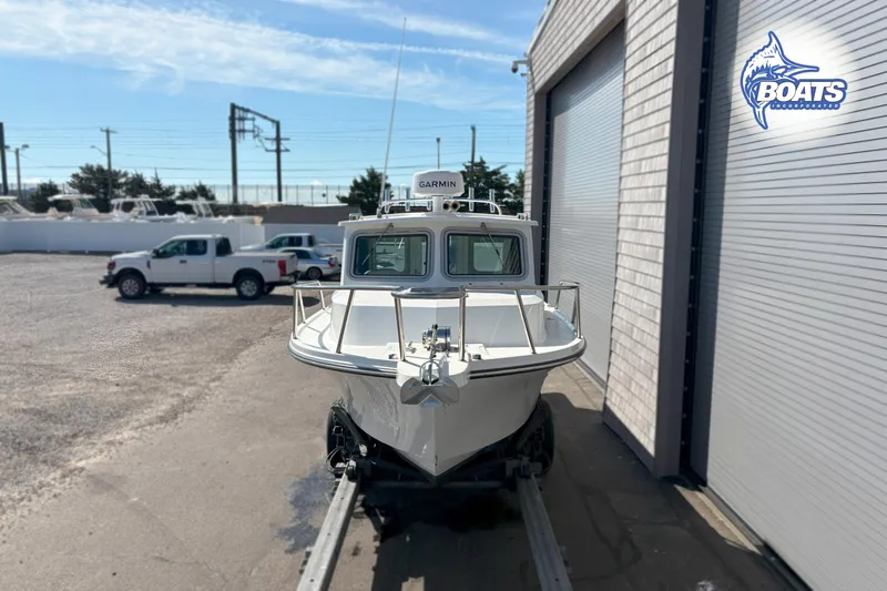 Slide: The Image of 2024 Parker 2320 SL Sport Cabin boat on trailer near garage, sunny day. - 2