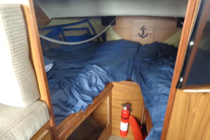 Slide: The Image of Cozy boat cabin interior with blue bedding and wooden accents, featuring a fire extinguisher. - 13