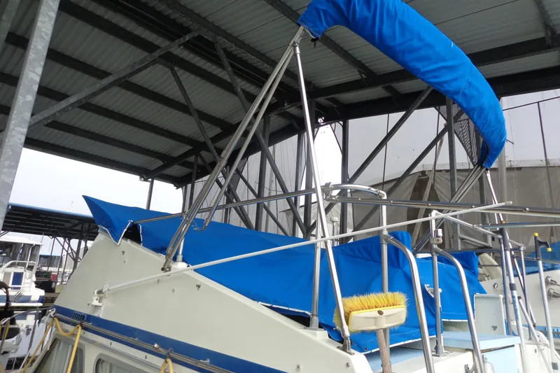 Slide: The Image of Boat with blue canopy and railing under a metal roof at a marina. - 4