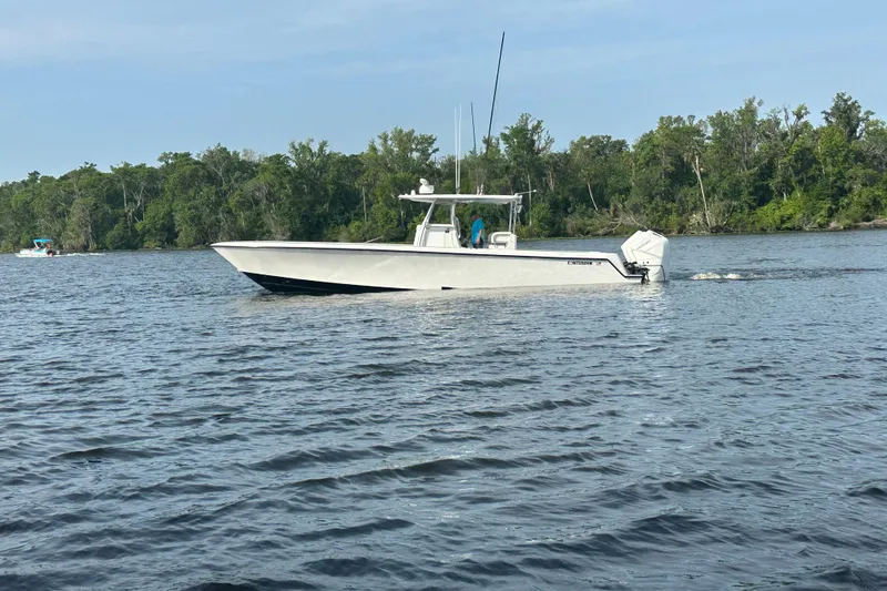 Slide: The Image of 2024 Contender 39 ST boat on trailer, parked near stadium under cloudy sky. - 11