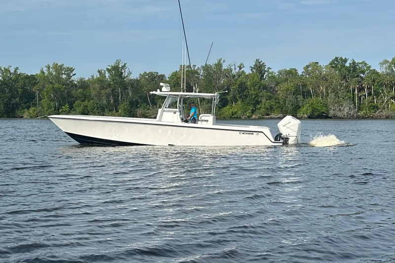 Slide: The Image of 2024 Contender 39 ST boat on Sport Trail trailer, parked in a lot under cloudy sky. - 12