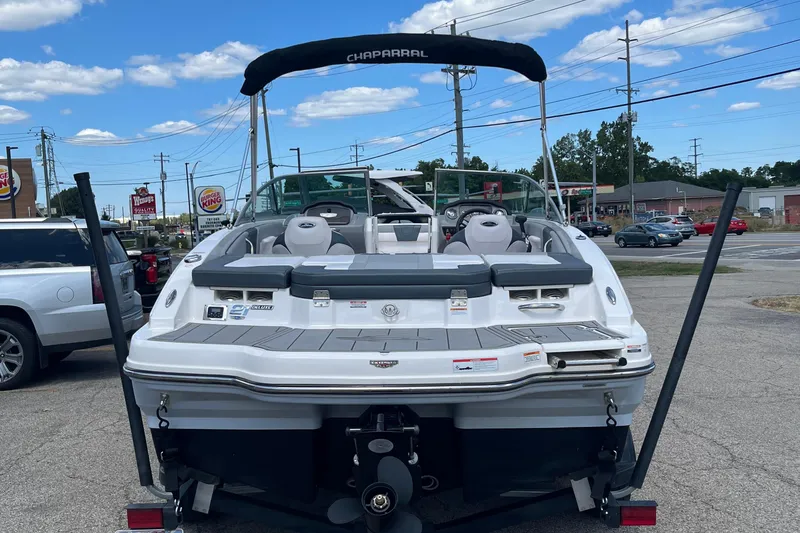 Slide: The Image of 2021 Chaparral 21 SSi boat parked, rear view, in a parking lot with clear skies. - 2
