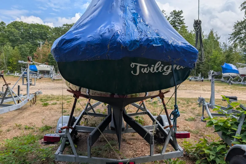 Slide: The Image of 1981 Cape Dory Typhoon sailboat named "Twilight" covered and on a trailer in a yard. - 2
