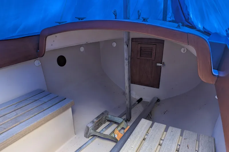 Slide: The Image of 1981 Cape Dory Typhoon sailboat interior with wooden benches and blue tarp cover. - 3