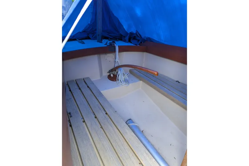 Slide: The Image of Interior of a 1981 Cape Dory Typhoon sailboat with wooden benches and blue tarp cover. - 5
