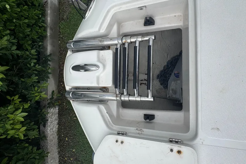 Slide: The Image of 2004 Hurricane 2600 boat ladder and anchor compartment, surrounded by greenery. - 13